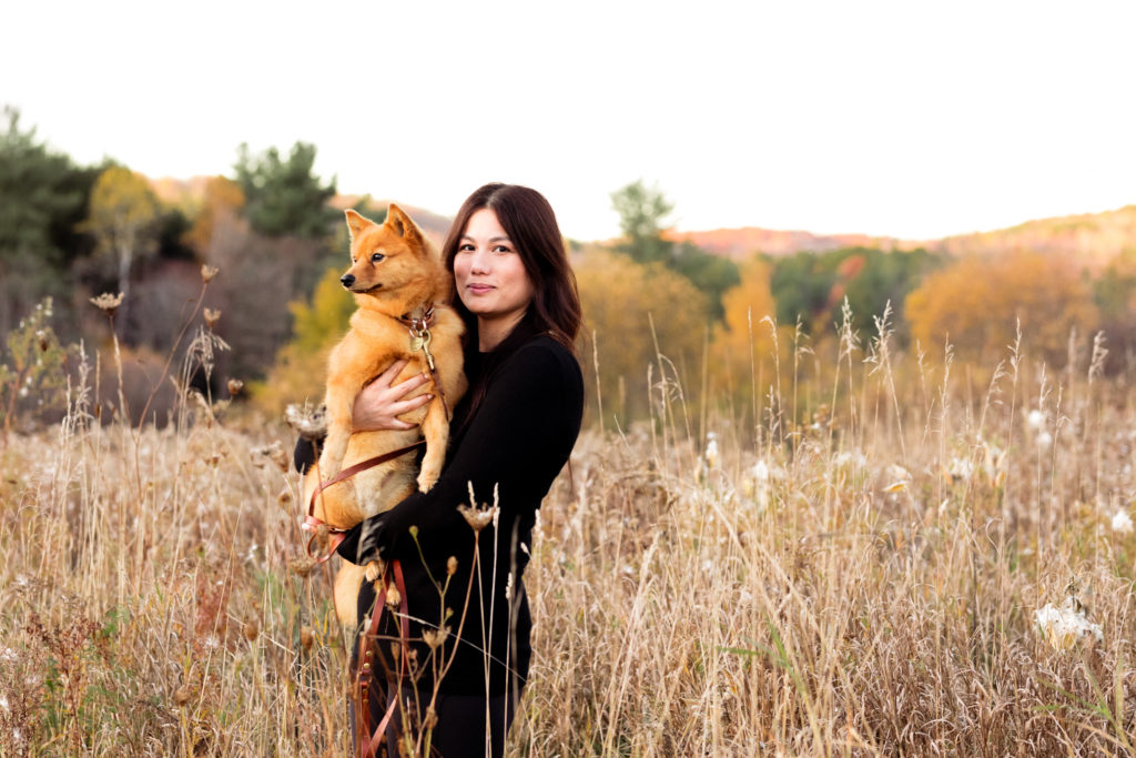 A woman holds her dog in the fall foliage in Northern Vermont.